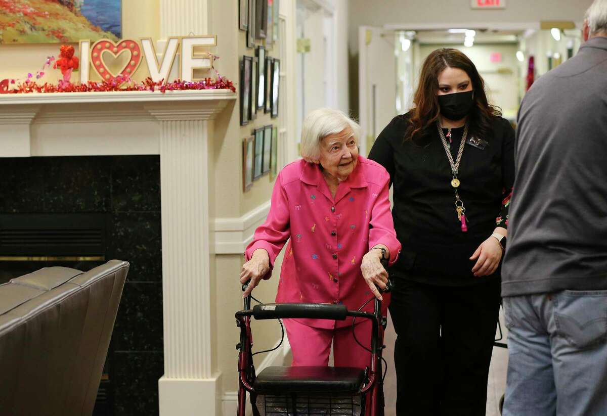 World War II veteran Maureen Davis gets escorted to lunch by Ruby Ballin, the activities director at her assisted living facility in Jourdanton, after Davis led a calisthenics class. She celebrated her 105th birthday Tuesday.