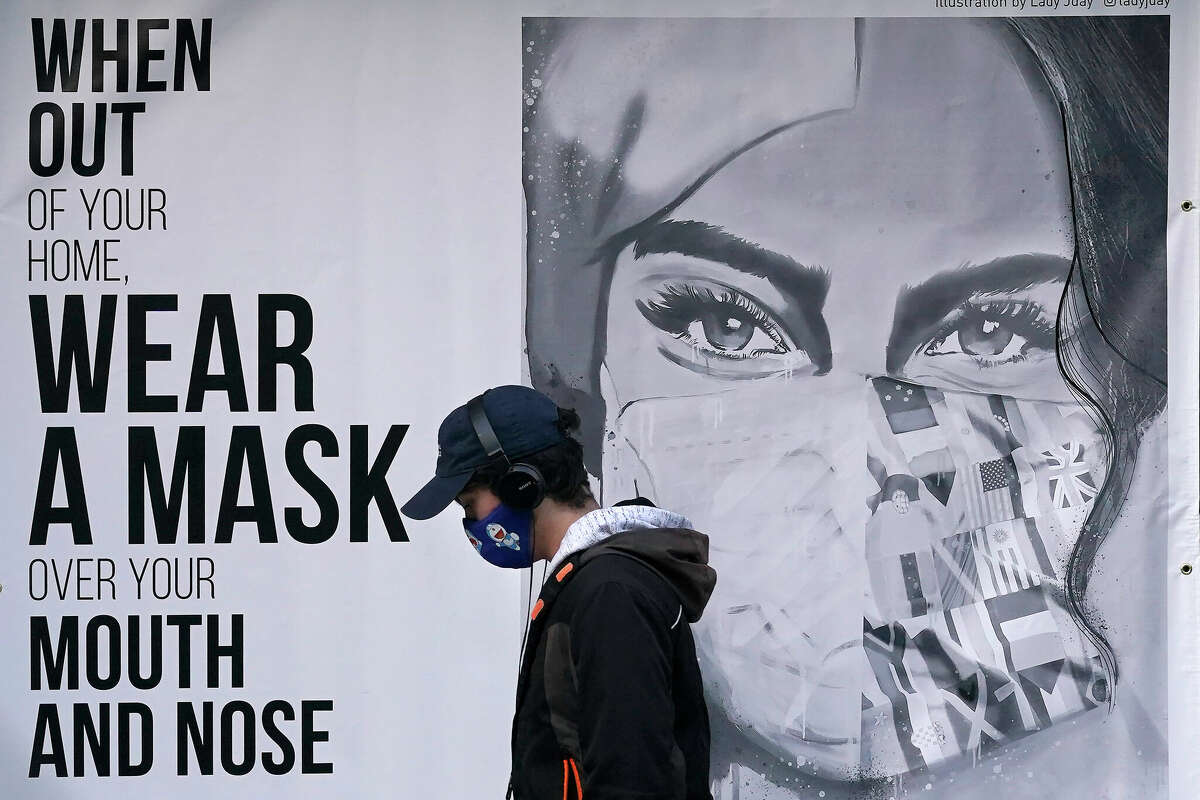 In this file photo, a pedestrian wearing a mask walks past a mural during the coronavirus outbreak in San Francisco.