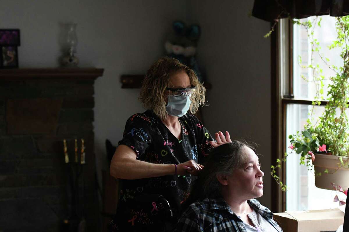 Home health aide Lenora Roylance combs the hair of Rosanne Sgueglia at Sgueglia’s home in Schaghticoke last month.