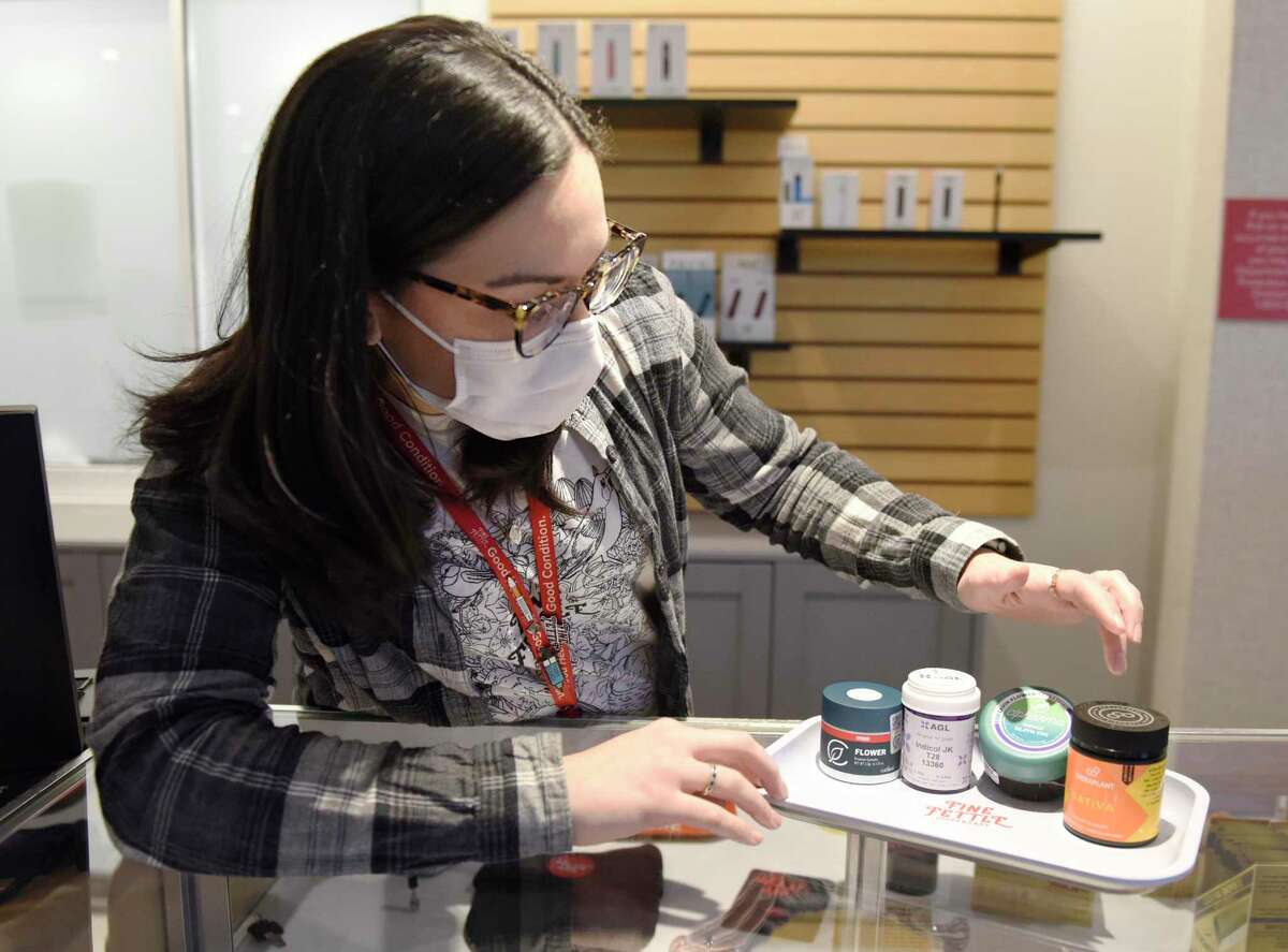 Assistant manager Marion Baxter, PharmD, shows cannabis flower from the four Connecticut growers at Fine Fettle medical cannabis dispensary in Stamford, Conn. Monday, Feb. 21, 2022. The dispensary opened its doors to patients on Monday providing a variety of prescribed medical cannabis items and accessories.