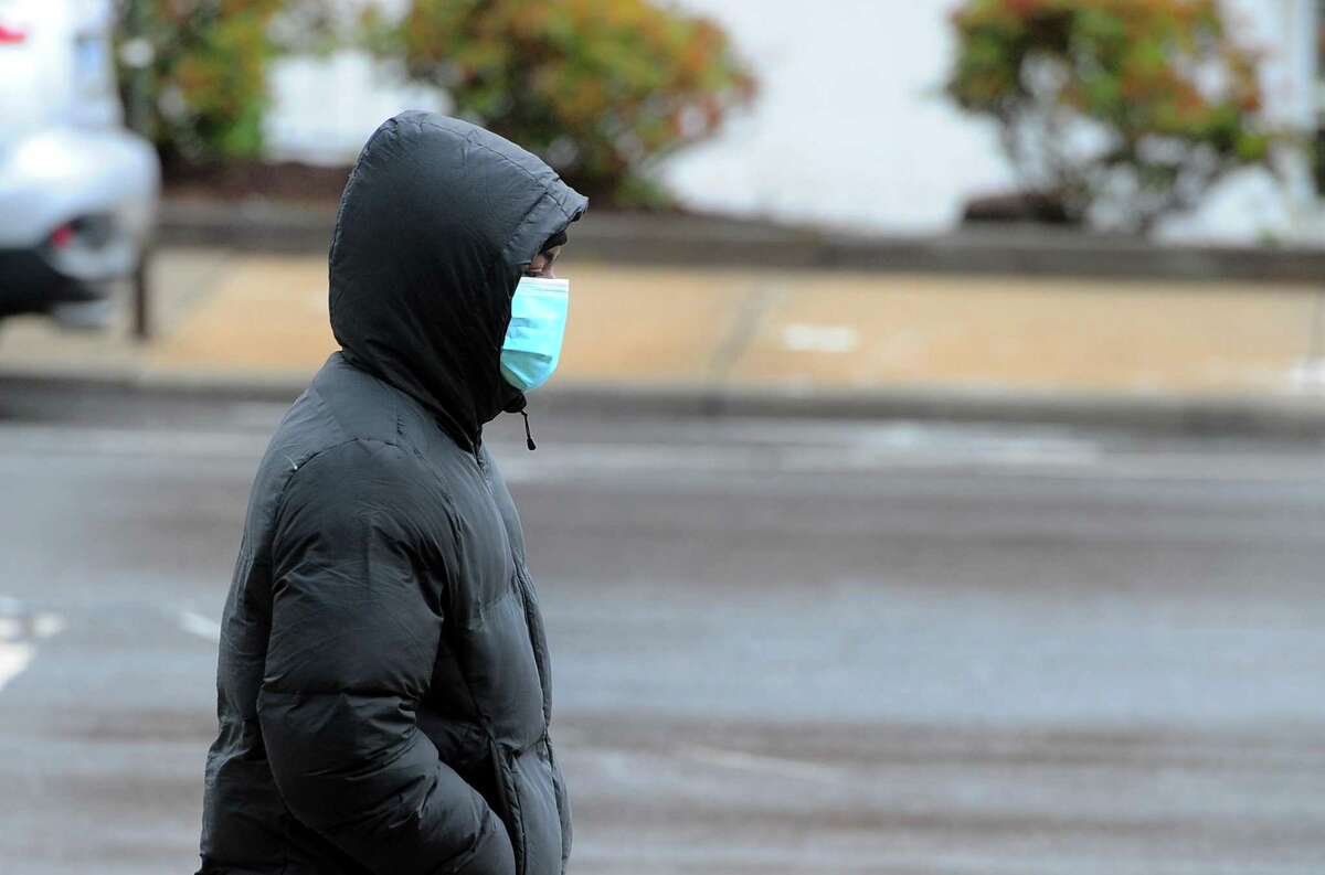 A pedestrian wears a face mask as he walks along Main Street in Bridgeport, Conn., on Tuesday Apr. 21, 2020. Mayor Joe Ganim is lifting the city-wide mask mandate starting Wednesday.