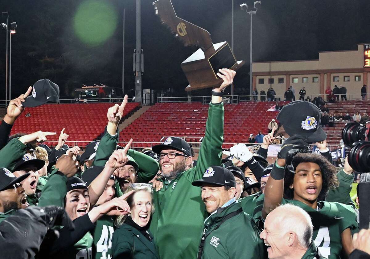 Coach Barry McLaughlin holds the championship trophy aloft after his team beat Northview, 48-29, on Dec. 11 to win the state Division 4A title.