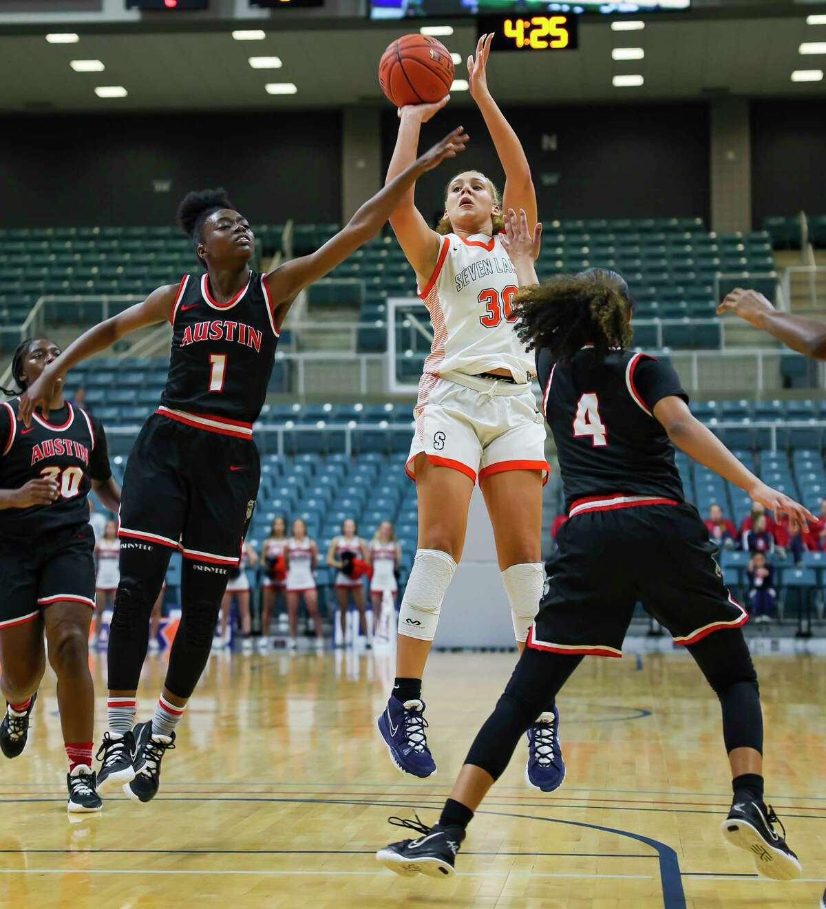 Seven Lakes forward Justice Carlton (30) shoots over guard Andrea Sturdivant (1) and guard Aminah Dixon (4) during the first half of a Region III-6A quarterfinals game between the Seven Lakes Spartans and Austin Bulldogs, Tuesday, Feb. 22, 2022, at the Merrell Center in Katy.
