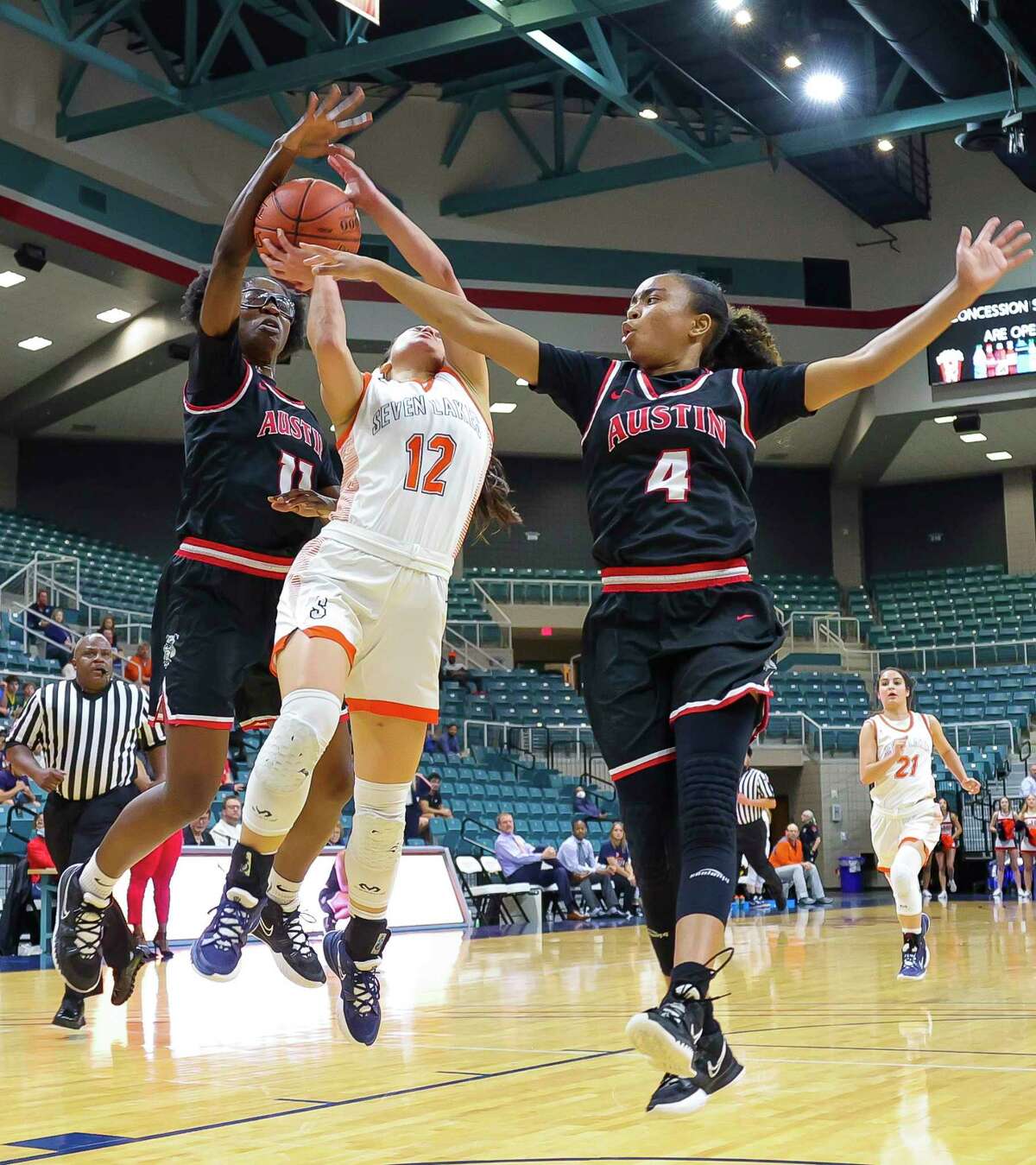 Seven Lakes guard Cailyn Tucker is defended by Austin forward Kelechi Dike (11) and guard Aminah Dixon (4) during the first half of a Region III-6A quarterfinals game between the Seven Lakes Spartans and Austin Bulldogs, Tuesday, Feb. 22, 2022, at the Merrell Center in Katy.