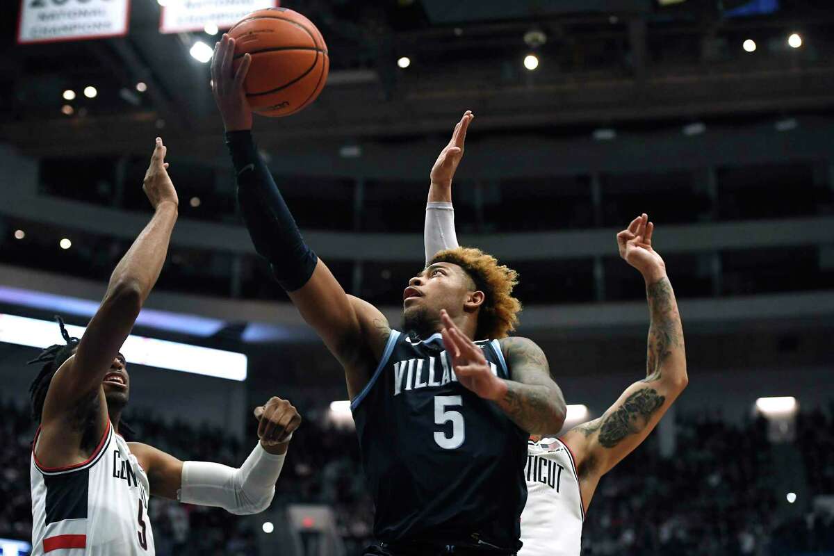 Villanova's Justin Moore shoots as Connecticut's Isaiah Whalen, left, and Tyrese Martin, back, defend during the first half of an NCAA college basketball game Tuesday, Feb. 22, 2022, in Hartford, Conn. (AP Photo/Jessica Hill)