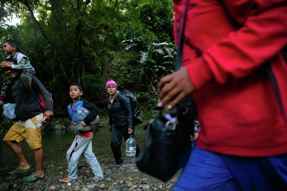 Migrants cross the Río Muerto as they enter the Darién Gap jungle on their way north assisted by guides, Saturday, Nov. 6, 2021, in Acandí.