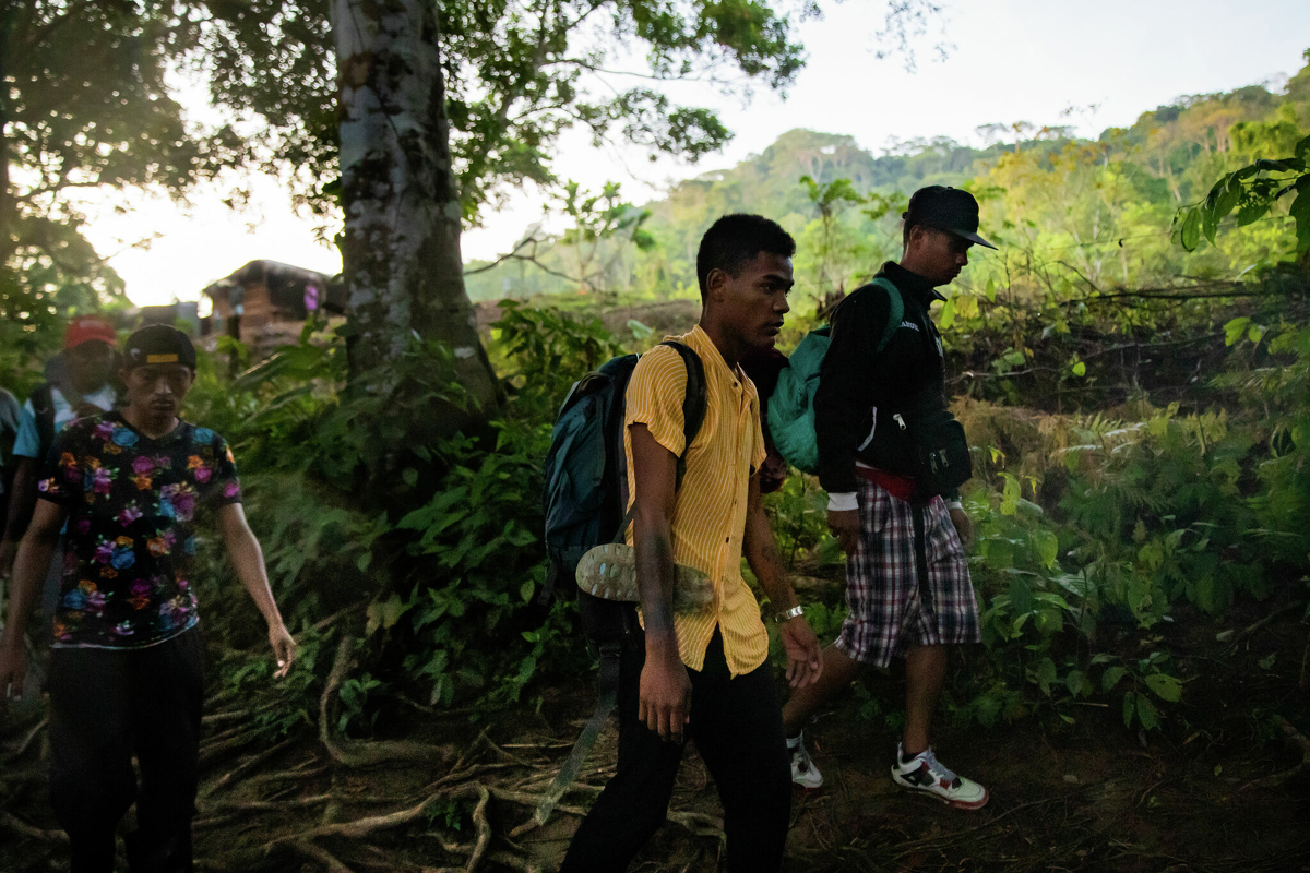 Venezuelan migrant Jesús Fernández, center, 24, and his cousin Carlos Fernandez, right, from San Felipe Yaracuy, walk a trail on their way to the Darién Gap along the Río Muerto, Nov. 6, 2021, in Acandí, Colombia.