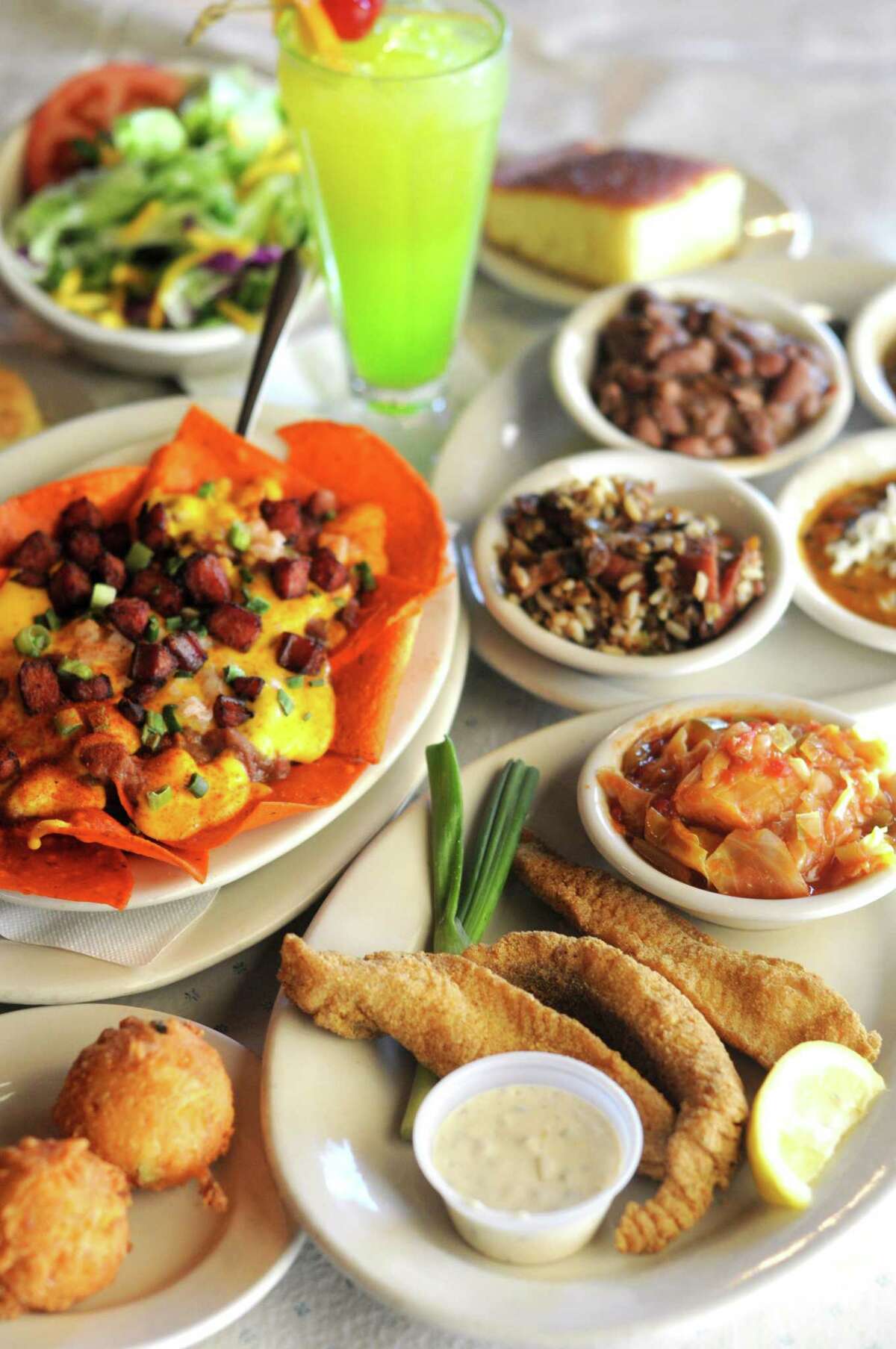 A selection of Louisiana-inspired classics at Acadiana Café including (clockwise from front) fried catfish with stewed cabbage, Cajun Nachos and a sampler tray with bowls of of gumbo, red beans and rice, crawfish étouffée and jambalaya