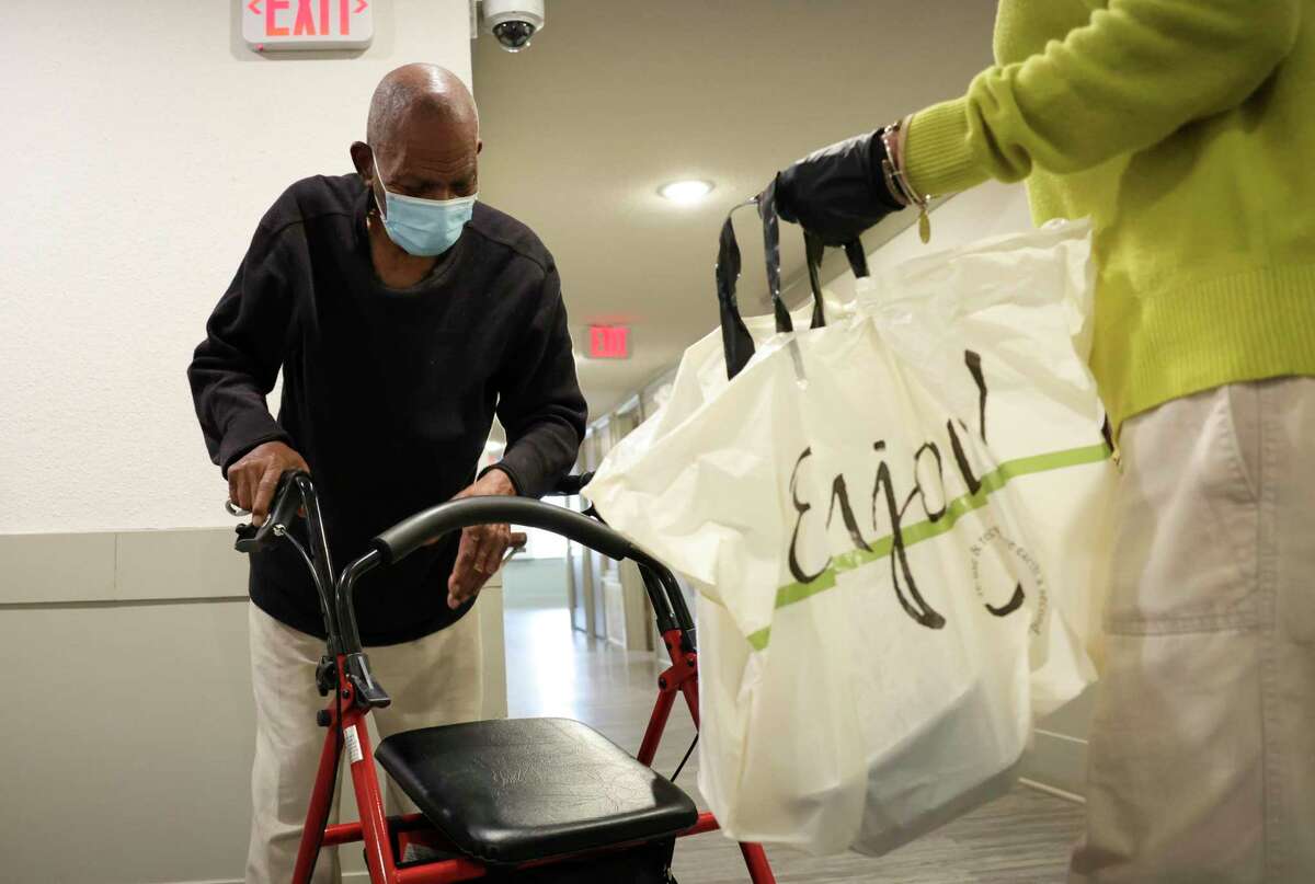 Service Coordinator Maxine Blakes carries meals provided by Lucille’s 1913 Conscious Community Collective to senior resident Robert Fennie at a senior living apartment complex on Feb. 10, 2022, in Houston. The nonprofit has been providing 150 meals per day and four days a week to the apartment complex, where seniors face food insecurity.