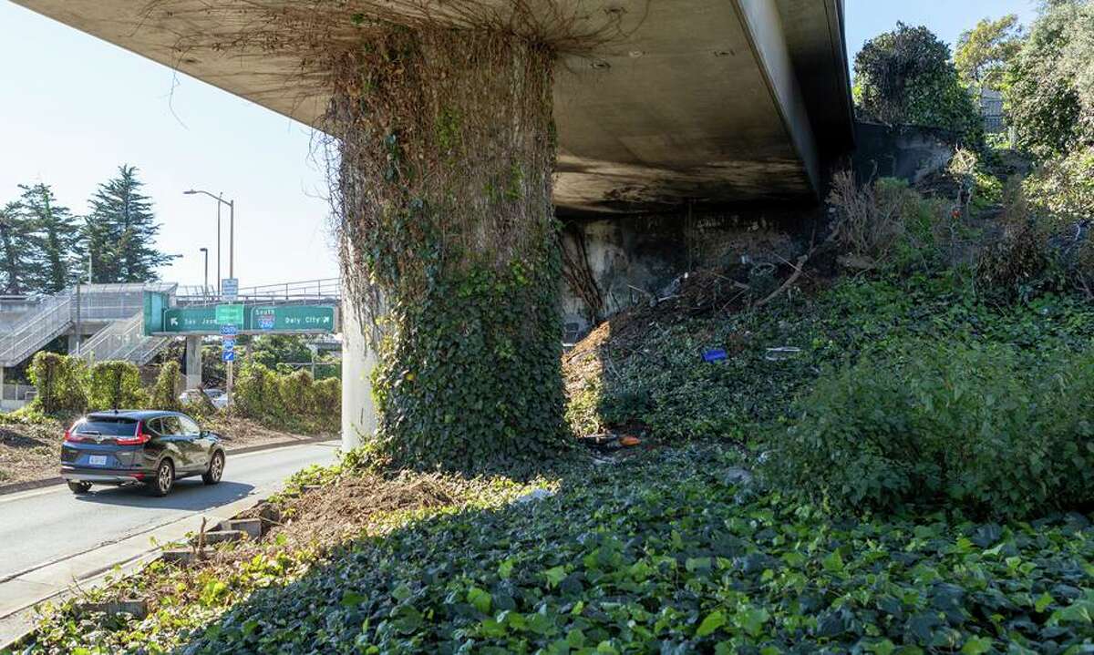 一辆汽车经过位于博斯沃思街匝道上的无家可归者营地的遗迹，该匝道位于旧金山格伦公园附近的I-280南行。