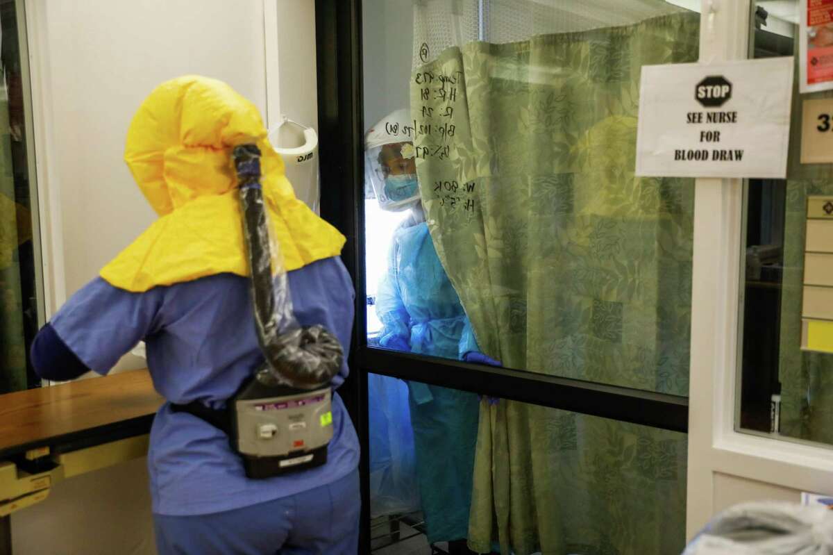Nurse Heather Barigian (right) gets assistance while working in an isolation room on the COVID ward at Salinas Valley Memorial Hospital in Salinas, Calif.