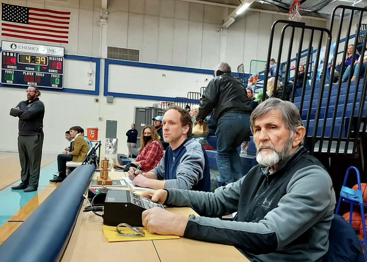 Longtime volunteer Jim Perry, right, watches the action as he operates the scoreboard during a ninth-grade basketball game this season at Meridian Early College High School. It was one of three local games he worked that evening. Matt Olmsted (left) keeps the scorebook. 