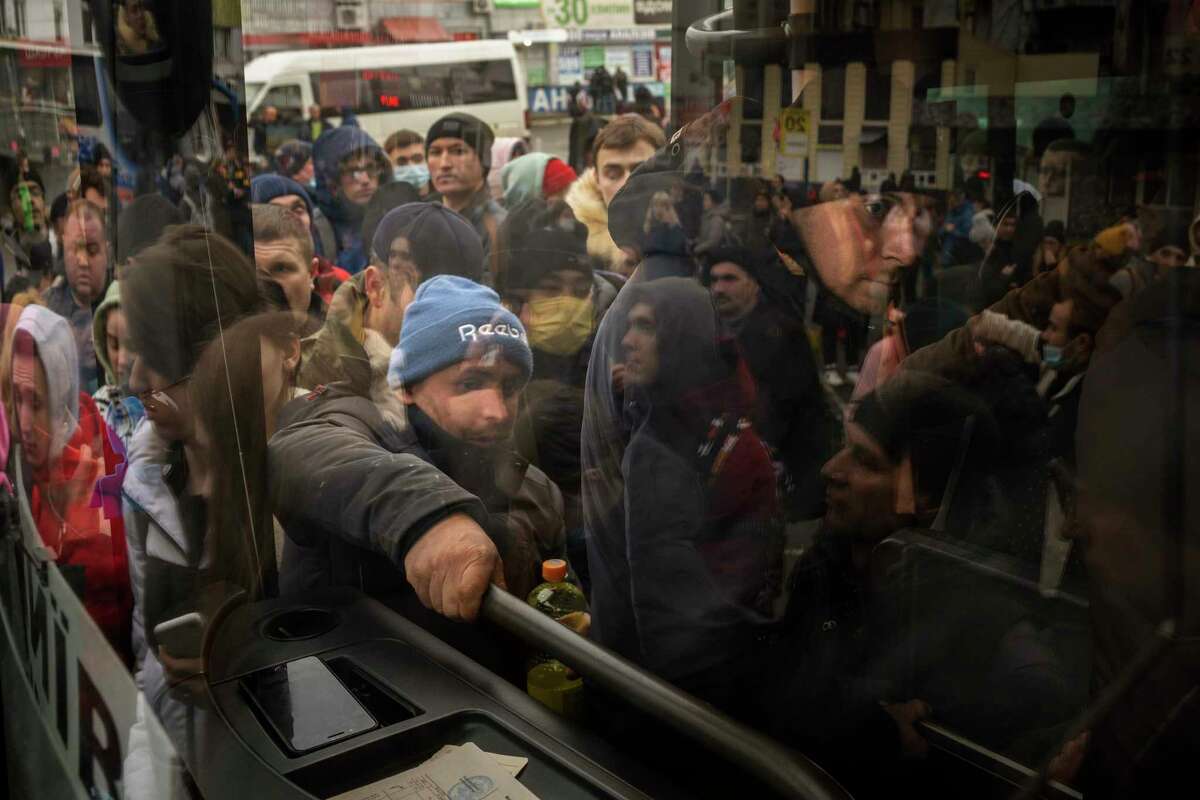 People try to get on a bus as they leave Kyiv, Ukraine, Thursday, Feb. 24, 2022. Russia launched a wide-ranging attack on Ukraine on Thursday, hitting cities and bases with airstrikes or shelling, as civilians piled into trains and cars to flee.