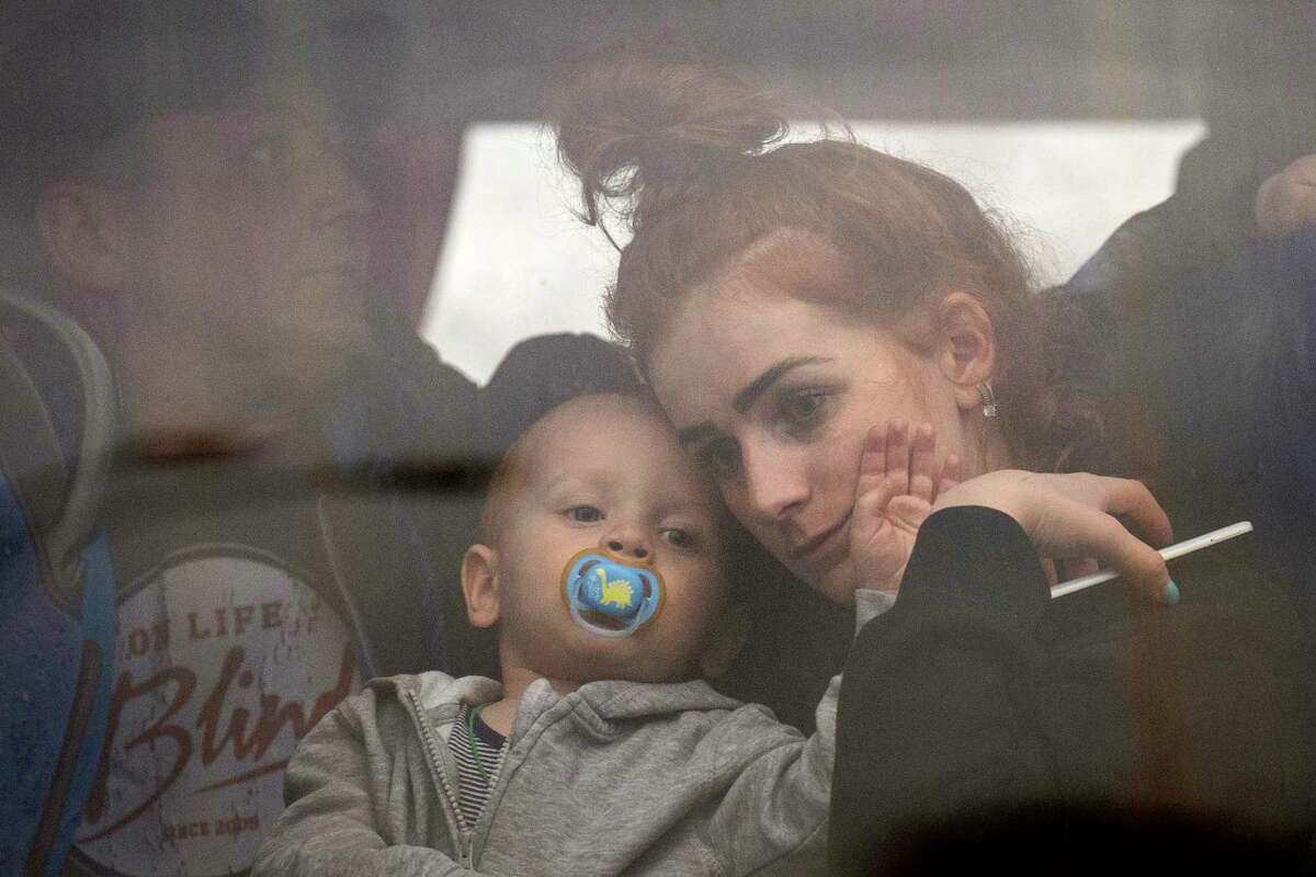 A woman holds her baby inside a bus as they leave Kyiv, Ukraine, Thursday, Feb. 24, 2022. Russia launched a wide-ranging attack on Ukraine on Thursday, hitting cities and bases with airstrikes or shelling, as civilians piled into trains and cars to flee.