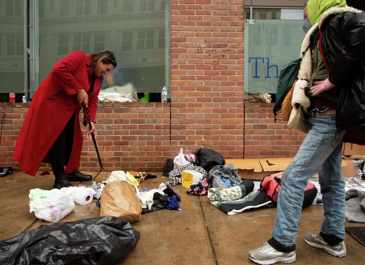 Kiki Aguero sweeps trash from the sidewalk as she moves her belongings from the sidewalk outside The Beacon as it starts to rain on Jan. 31, 2022.