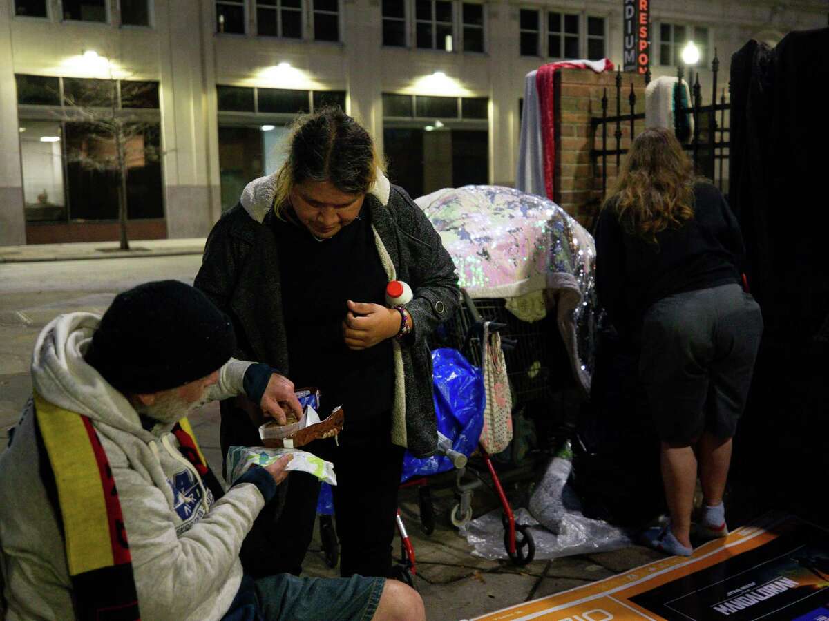 Kiki Aguero, center, offers chocolate chip cookies to her friend Alan Schkade outside The Beacon on Feb. 1, 2022.