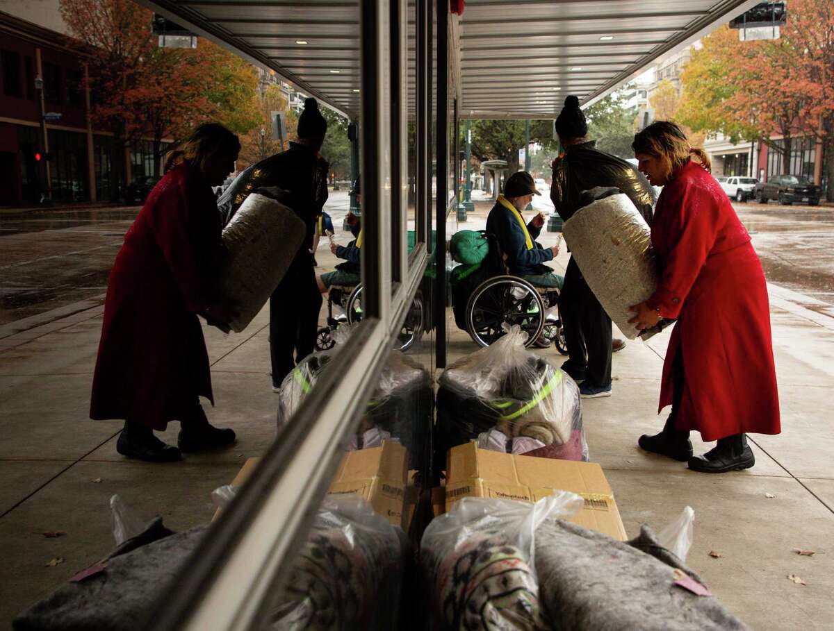 Kiki Aguero and her friends move their belongings to a sidewalk where a building overhang provides shelter from the rain Jan. 31, 2022.