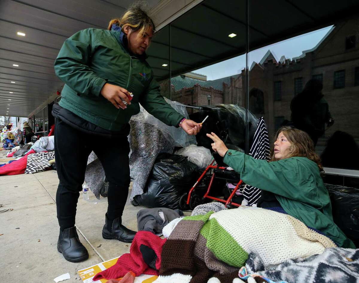 Kiki Aguero, left, hands off a cigarette to Lillard Knotts on Feb. 3, 2022, in downtown Houston.