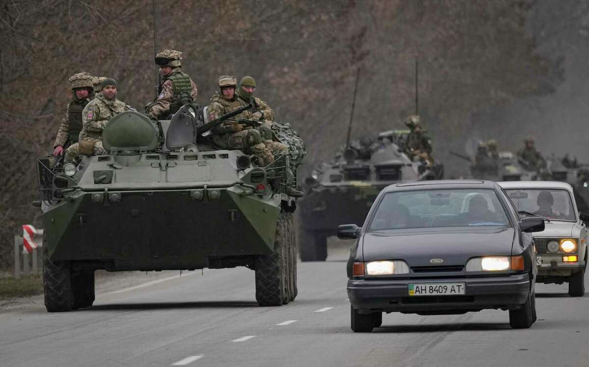 Ukrainian servicemen sit atop armored personnel carriers driving on a road in the Donetsk region, eastern Ukraine, Thursday, Feb. 24, 2022. Russian President Vladimir Putin on Thursday announced a military operation in Ukraine and warned other countries that any attempt to interfere with the Russian action would lead to "consequences you have never seen."