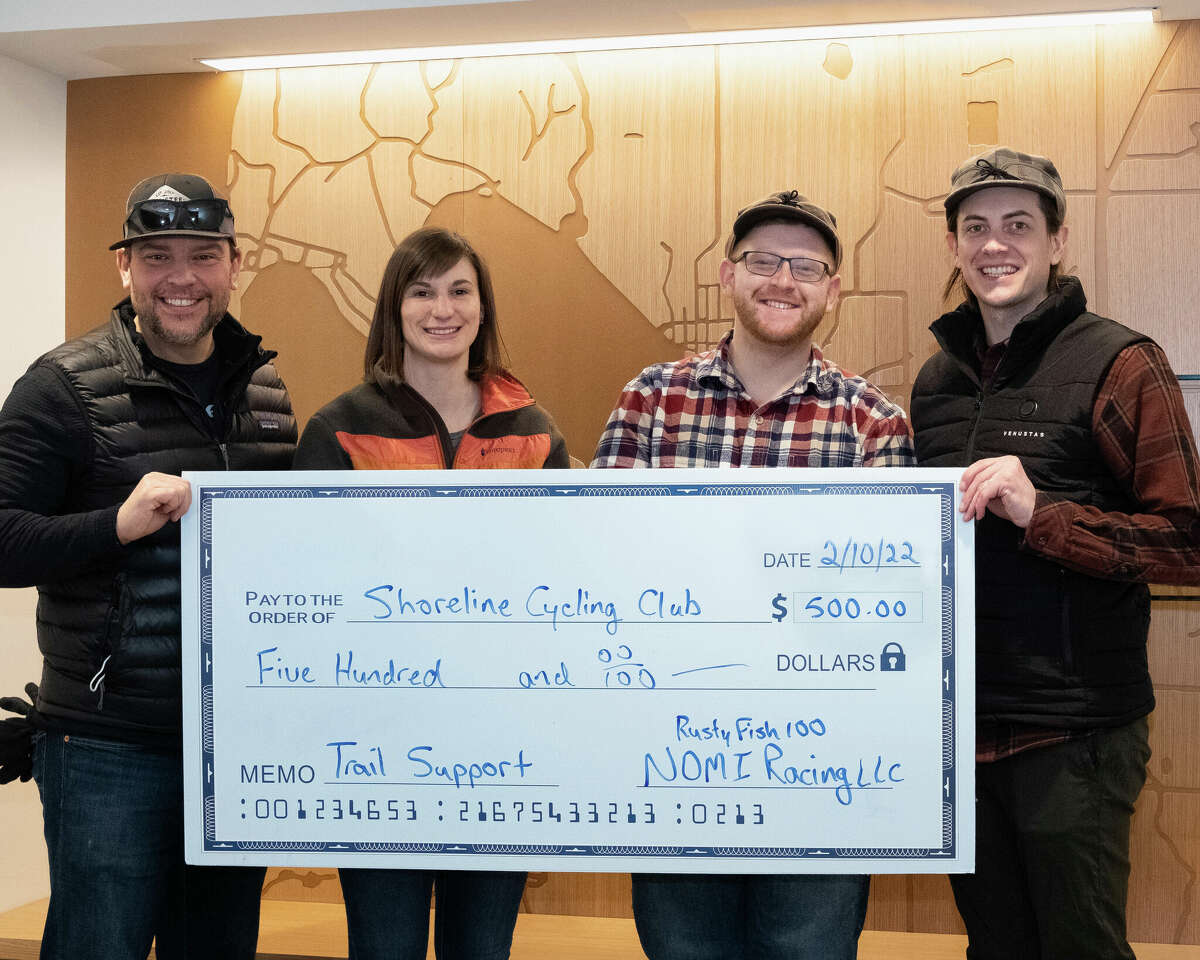 Representatives from NOMI Racing LLC donate a check to the Shoreline Cycling Club to support trail maintenance and operations in Manistee County.