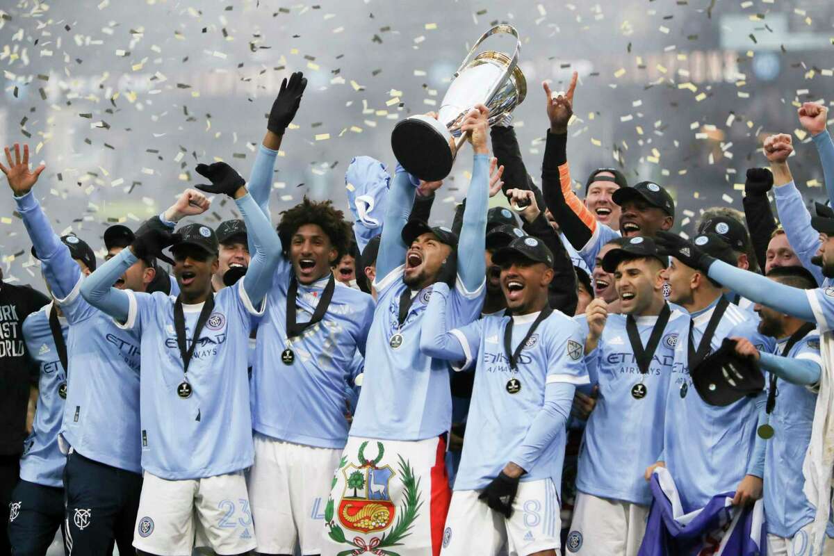 FILE - New York City FC players celebrate with the trophy after their penalty kick shootout win over the Portland Timbers in the MLS Cup soccer game, Saturday, Dec. 11, 2021, in Portland, Ore. The league's 28 teams kick off this weekend. To make way for the World Cup, the league shifted to it earliest start ever and a quicker finish. NYCFC is the defending MLS Cup winner (AP Photo/Amanda Loman, File)