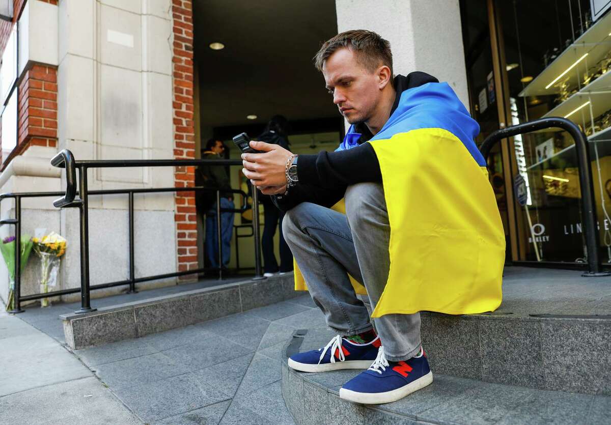 Maksym Zubkov, a UC Berkeley student from Ukraine who has family and friends there, sits outside the Ukrainian consulate as he watches the news of the country’s invasion by the Russian army.