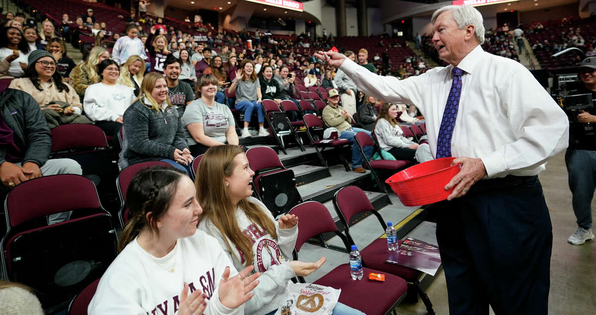 Texas A&M head coach Gary Blair, right, throws out candy to the crowd at Reed Arena before his final NCAA college basketball game at Reed Arena, against South Carolina, Thursday, Feb. 24, 2022, in College Station, Texas. Blair is retiring at the end of the season. (AP Photo/Sam Craft)
