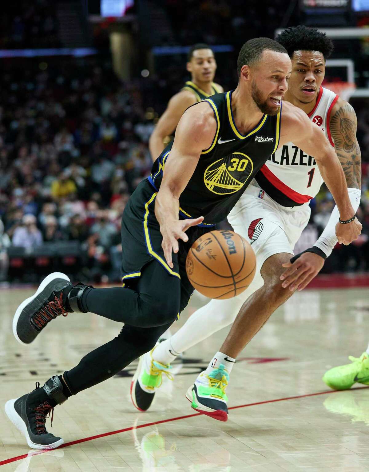 Golden State Warriors guard Stephen Curry, left, dribbles past Portland Trail Blazers guard Anfernee Simons during the first half of an NBA basketball game in Portland, Ore., Thursday, Feb. 24, 2022. (AP Photo/Craig Mitchelldyer)
