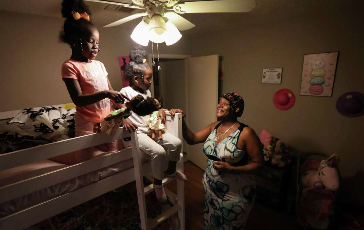 Chevette Chambers, from right, smiles as she watches her granddaughters Xaleah Prince, 6, and her twin sister Xalayah play with donated toys Thursday, Feb. 3, 2022, at their home in Houston. Chambers said she felt “blessed” for the donated toys.