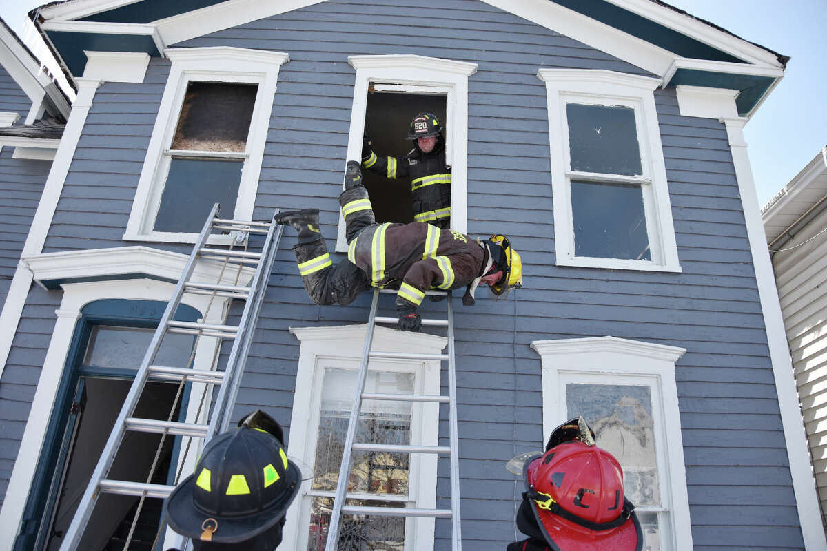 The house on 269 Fifth St. was the site of training for the Manistee City Fire Department. Shown is Brandon Nelson using a maneuver to go head first out a window and then turn facing the ladder and slide down the length of the ladder quickly.