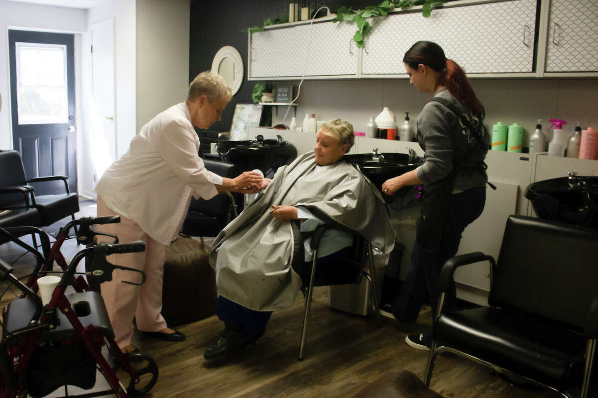 Elaine Embrey, left, hands her twin sister, Marge, center, her mid-day medication during an appointment at 989 Salon and Spa on Friday, Sept. 3, 2021 in Bay City. The sisters have alarms set on their phone that alert them when it's time to take their medication.