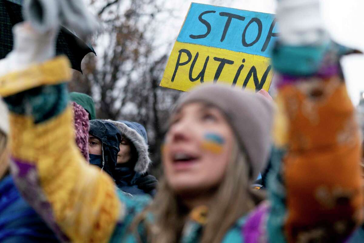 A sign reads "Stop Putin" in the colors of the Ukrainian flag as Ukranian Oleksandra Yashan of Arlington, Va., foreground wears the colors of the Ukrainian flag on her cheeks as she chants during a vigil to protest the Russian invasion of Ukraine in Lafayette Park in front of the White House in Washington, Thursday, Feb. 24, 2022. (AP Photo/Andrew Harnik)