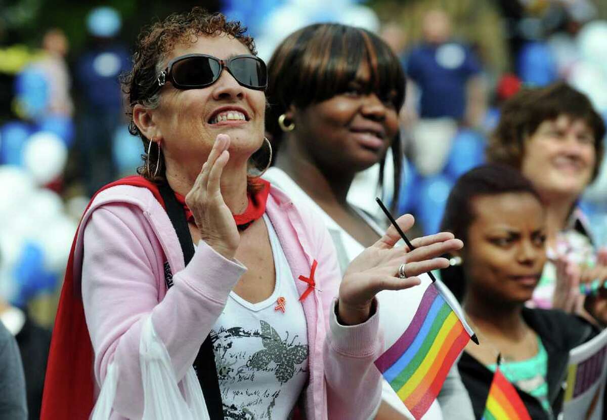Maria Aponte, of Albany, left, joins in singing "We Shall Overcome" during the 14th annual AIDSWalk and 5K Run on Sunday in Albany's Washington Park. (Cindy Schultz / Times Union)