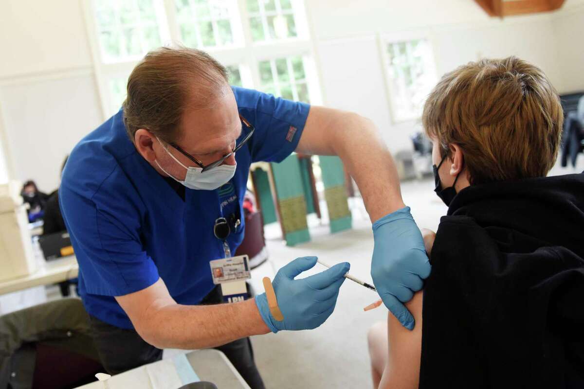 Scott Connelly, LPN, gives a COVID booster shot to Mark McNamara, 15, at the Person to Person Darien branch on the Saint Luke’s Parish campus in Darien onTuesday, Feb. 22. Person to Person hosted a free vaccination clinic in partnership with the Connecticut Department of Public Health for both initial and booster COVID vaccines for those ages five and up.