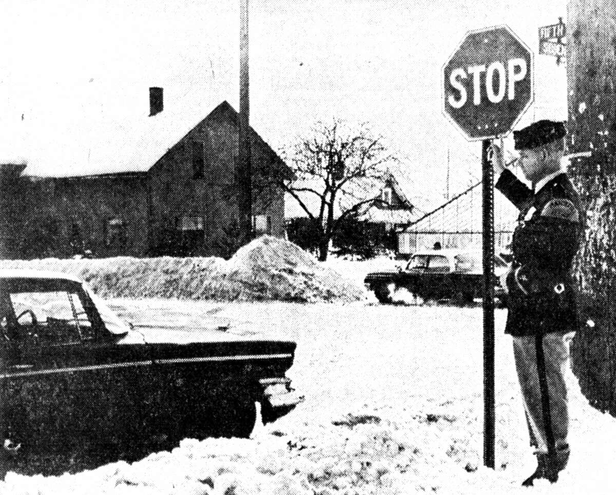 Officer Ed Alfred of the Manistee City Police Department points out the new stop sign at the Sibben and Fifth Street intersection. Traffic heading south on Sibben Street must now stop for Fifth Street. The photo was published in the News Advocate on Feb. 28, 1962.