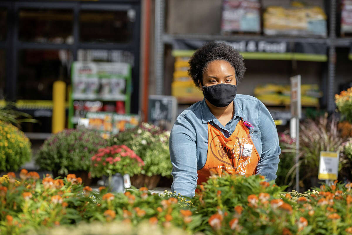 A Home Depot employee arranges plants in the gardening section. 