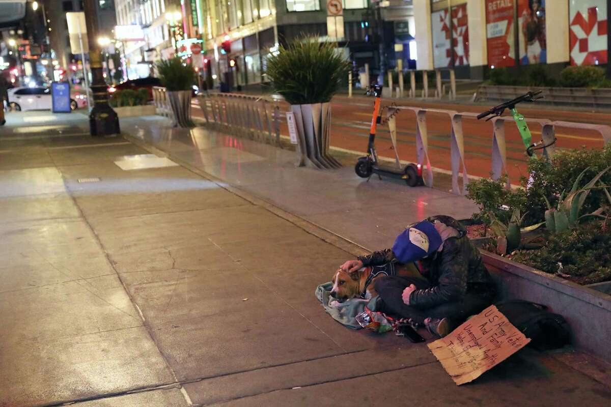 Homeless veteran CJ Peaslee, and his dog, Karma, sit on Powell Street as Point In Time one-night homeless count happens in San Francisco, Calif., on Wednesday, February 23, 2022. Preliminary findings from the count indicate that the city has fewer homeless residents this year than it did in 2019.
