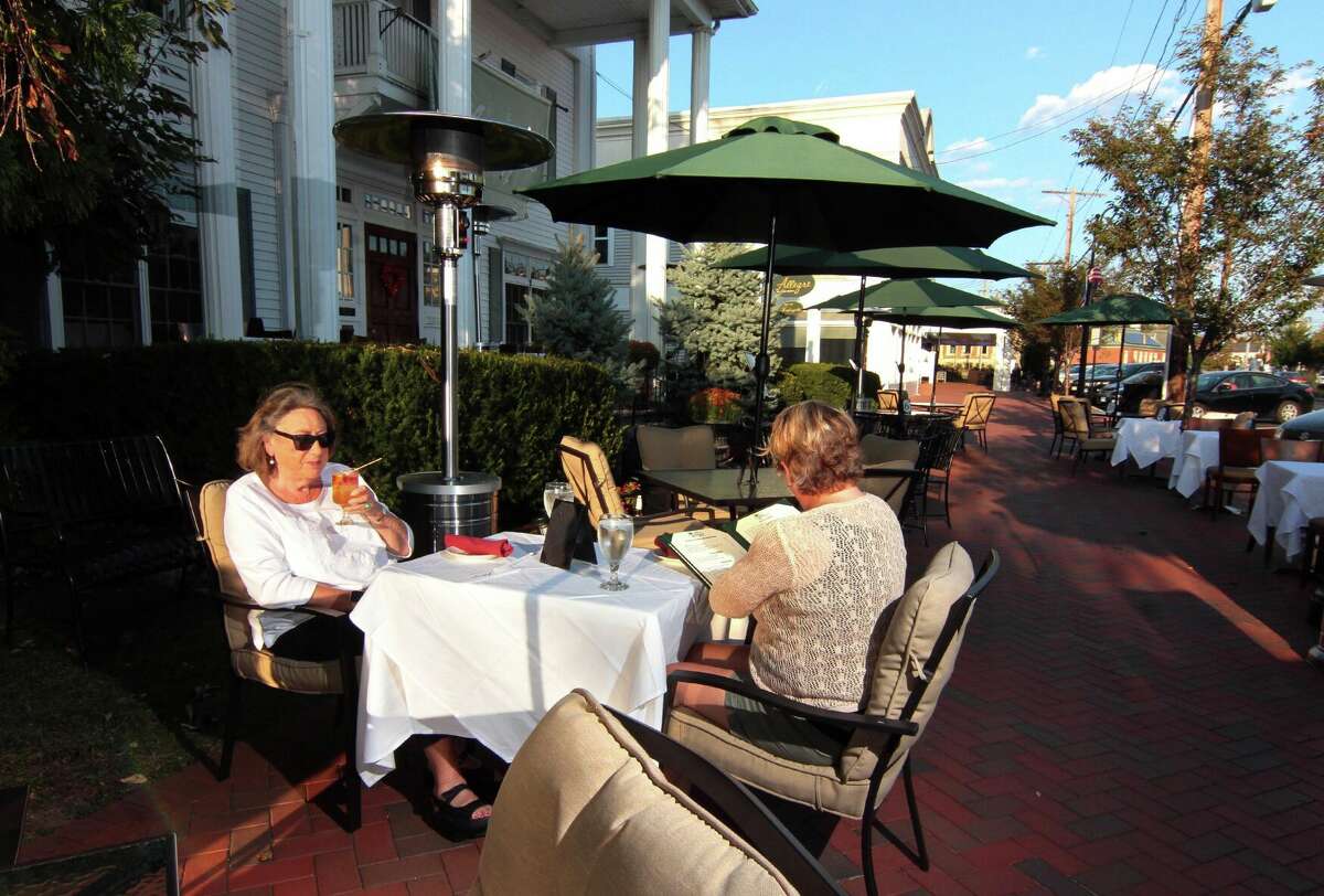 Marilyn Shaw, left, and her friend Linda Keating eat outside at Allegro restaurant in downtown Madison, Conn., on Wednesday Sept. 23, 2020. The town's Economic Development Commission is seeking applications for someone to "Light up Madison" and transform the town into a "spectacle" this winter.