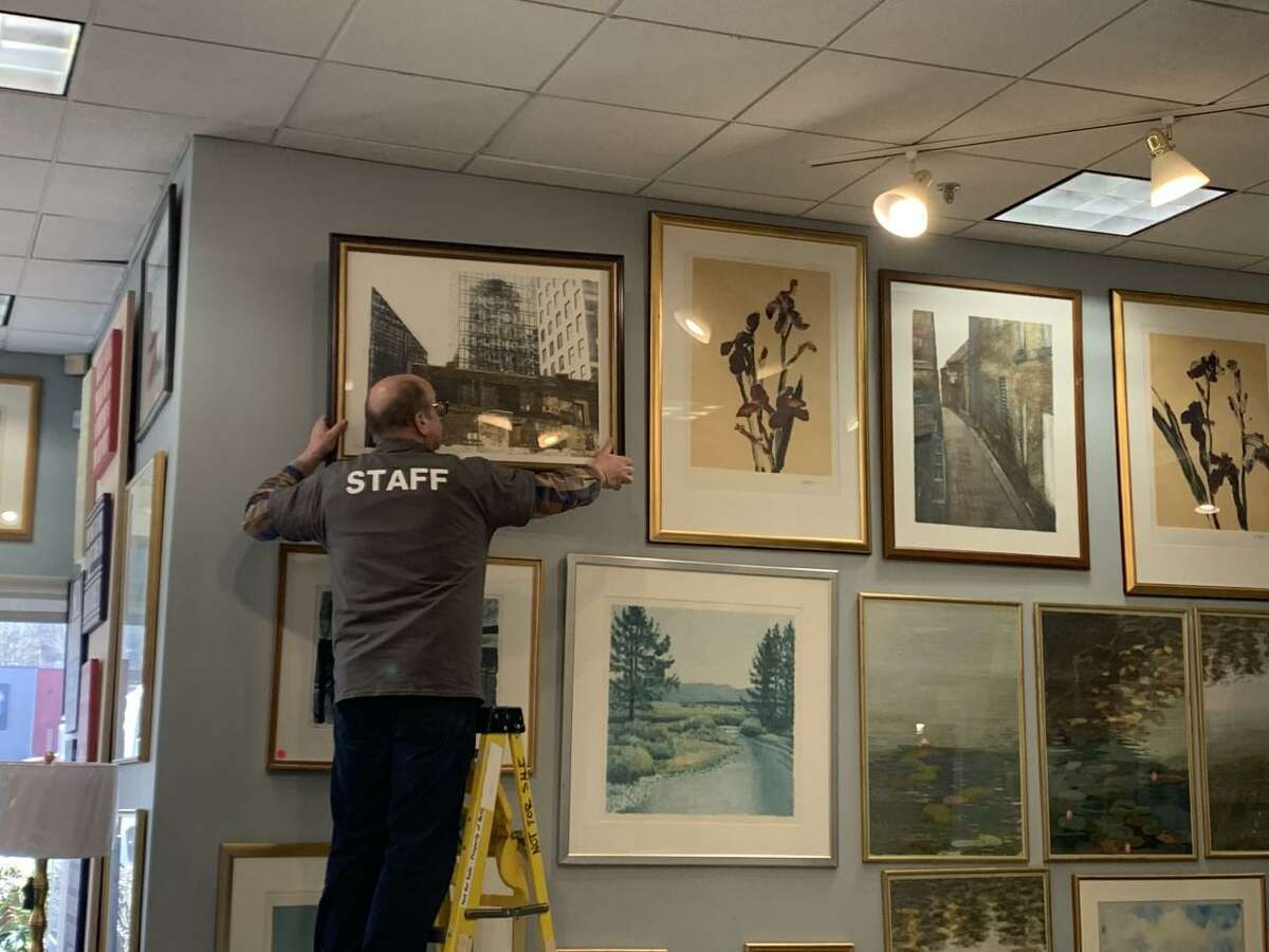 A staff member hangs a picture in the showroom of the new Habitat for Humanity ReStore location in Vernon.