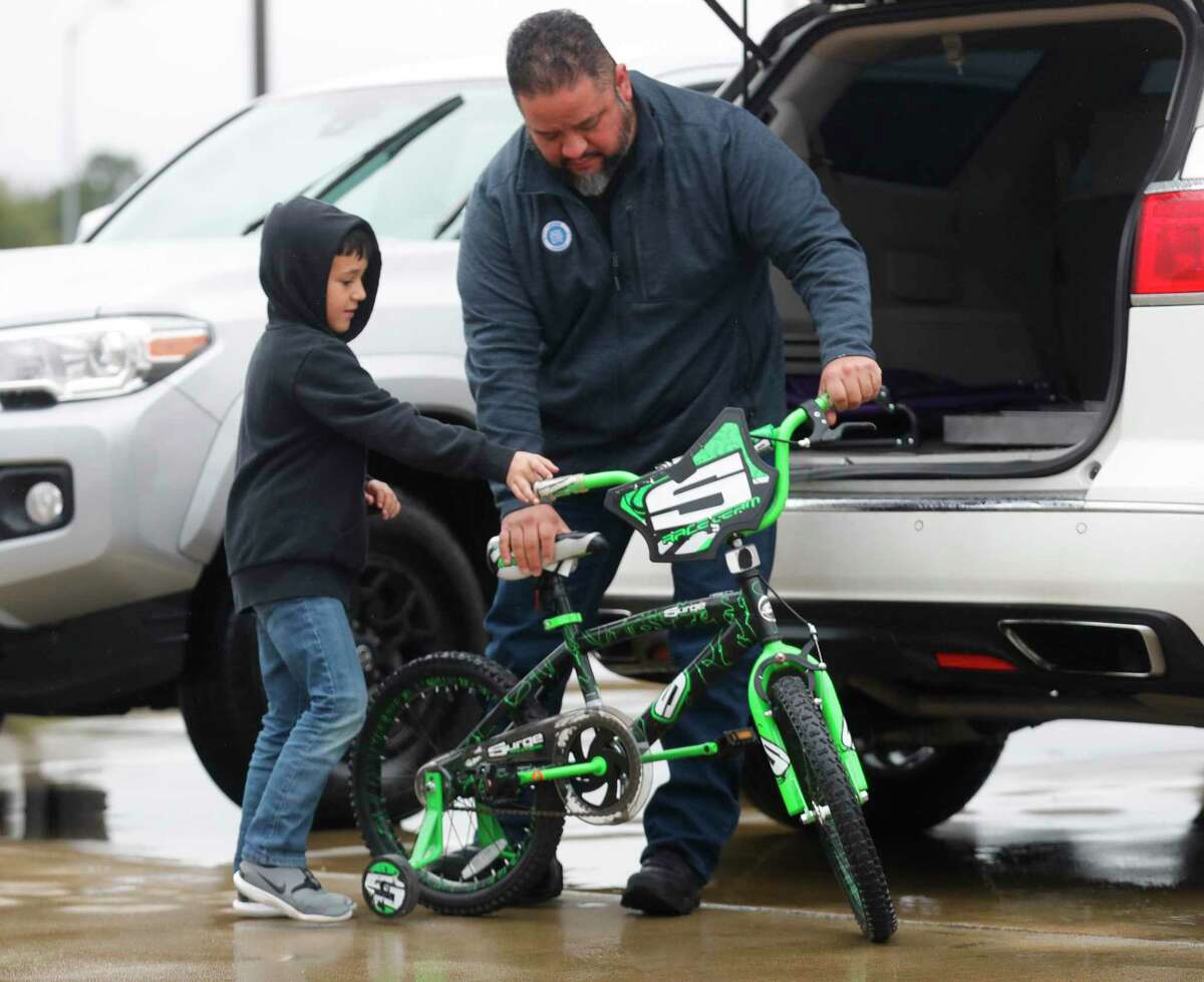 Joe Melchor gets his son Mason’s bike out of the car for Bradley Elementary’s annual bike rodeo, Saturday, Feb. 26, 2022, in Spring. Students and their families brought bikes and learned about bike safety, helmet checkups and went through a bicycle course.