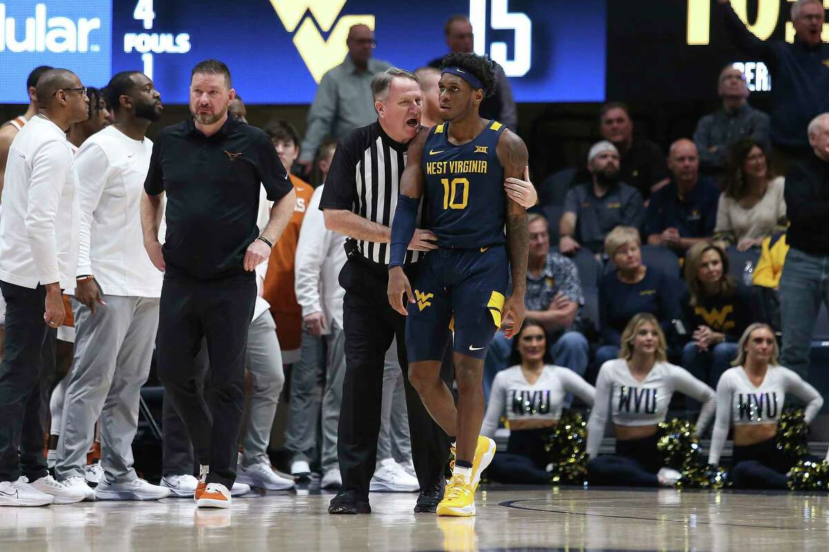 An official speaks with West Virginia guard Malik Curry (10) after a penalty against Texas forward Brock Cunningham (not pictured) during the first half of an NCAA college basketball game in Morgantown, W.Va., Saturday, Feb. 26, 2022. (AP Photo/Kathleen Batten)