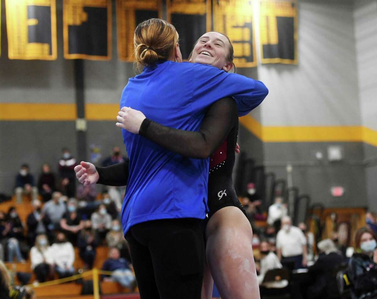 Fairfield Warde's Emma Johnson hugs her coach following a 9.65 score on the balance beam at the Class M gymnastics championships at Jonathan Law High School in Milford on Saturday.