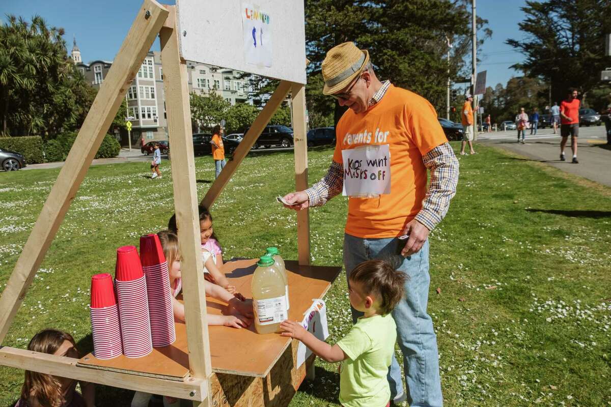 A parent buys lemonade from the lemonade stand, set up at the Mask Choice rally in San Francisco’s Golden Gate Park.