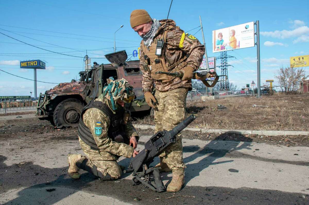 Ukrainian soldiers handle equipment from a damaged military vehicle after fighting in Kharkiv, Ukraine, Sunday, Feb. 27, 2022. The city authorities said that Ukrainian forces engaged in fighting with Russian troops that entered the country's second-largest city on Sunday.