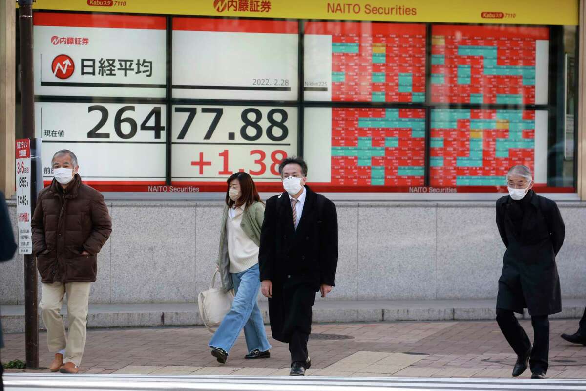 People walk by an electronic stock board of a securities firm in Tokyo, Monday, Feb. 28, 2022. Asian shares were mixed Monday as Western nations moved to tighten sanctions against Russia and President Vladimir Putin escalated tensions by ordering Russian nuclear forces put on high alert.