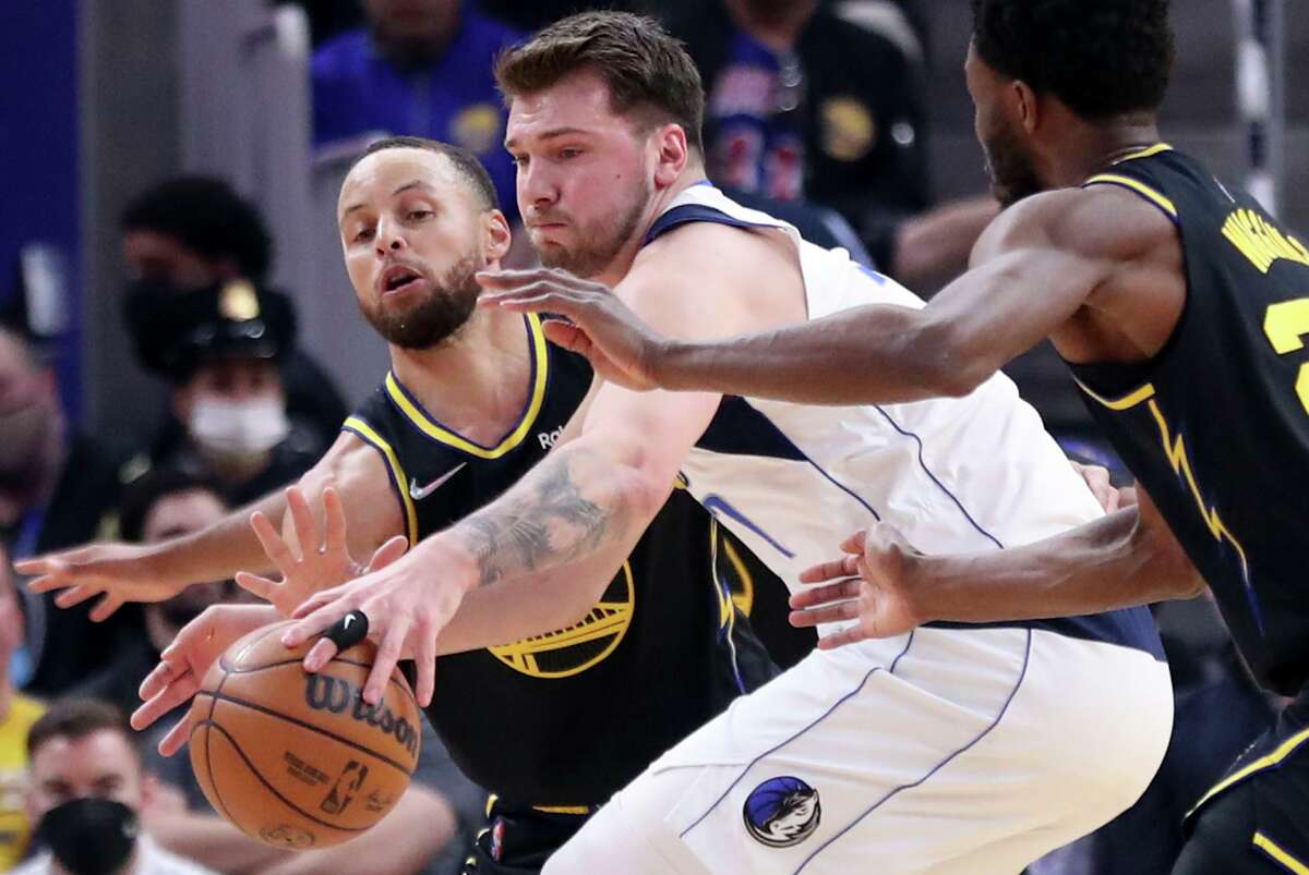 Golden State Warriors' Stephen Curry and Andrew Wiggins team up to steal the ball from Dallas Mavericks' Luka Doncic in 1st quarter during NBA game at Chase Center in San Francisco, Calif., on Sunday, February 27, 2022.