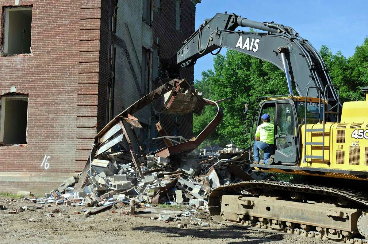 A excavator from AAIS Corp. in West Haven tears down part of Canaan House on the Fairfield Hills Campus in Newtown in 2016.