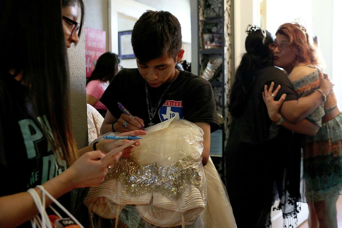 Southside High School students Esperanza Riuz, 17, and Jorge Rodriguez, 19, write thank you notes and share their thoughts about the event after choosing their outfits for prom at San Antonio Threads in San Antonio on Friday, May 11, 2018. At right, the organizers of Project Prom Dress, Pamela Espurvoa Allen, right, and Lucy Adame-Clark, embrace.