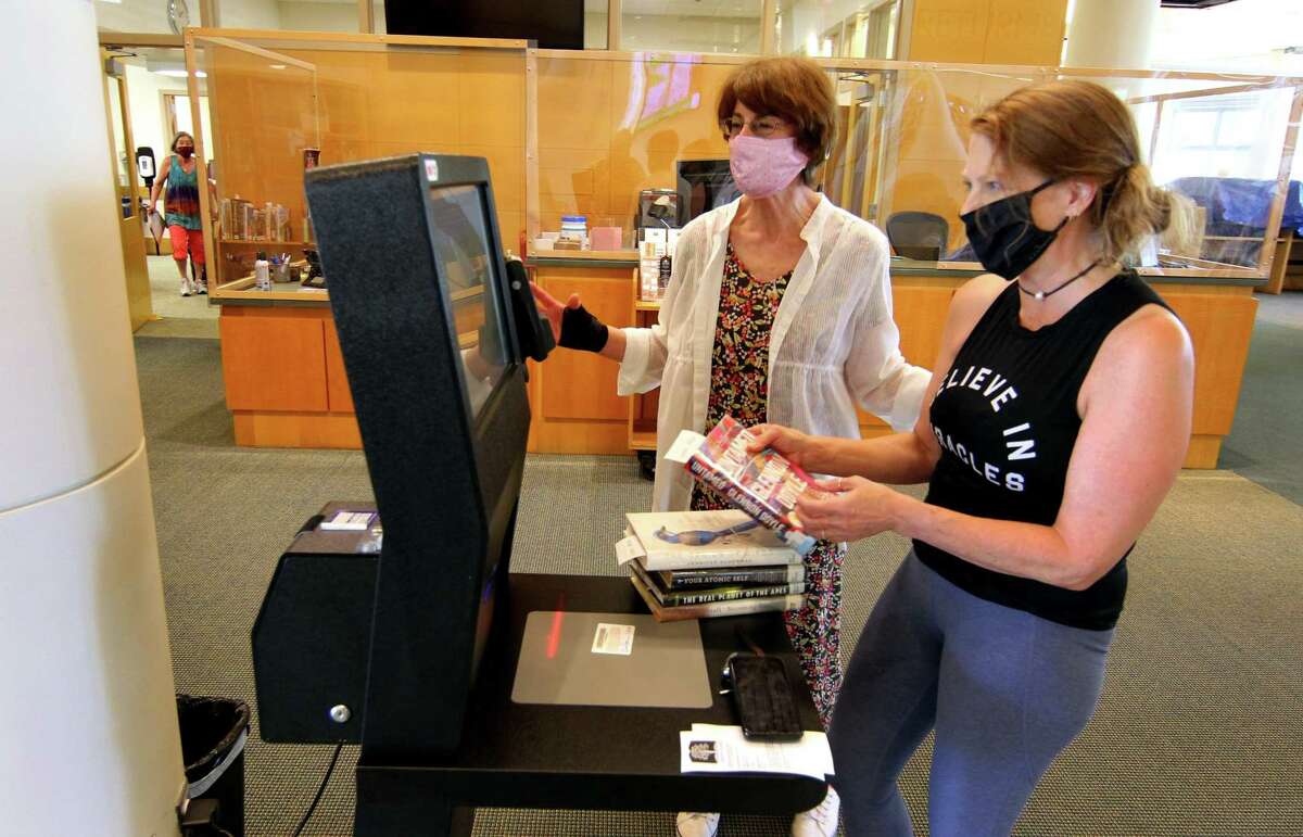 Masks will no longer be required at Greenwich Library, its branches in Cos Cob and Byram or at Perrot Memorial Library in Old Greenwich starting Tuesday. On June 10, 2021, Greenwich Library clerk Robin Terzi, center, helps Karie Loomis check books out on a new electronic kiosk.