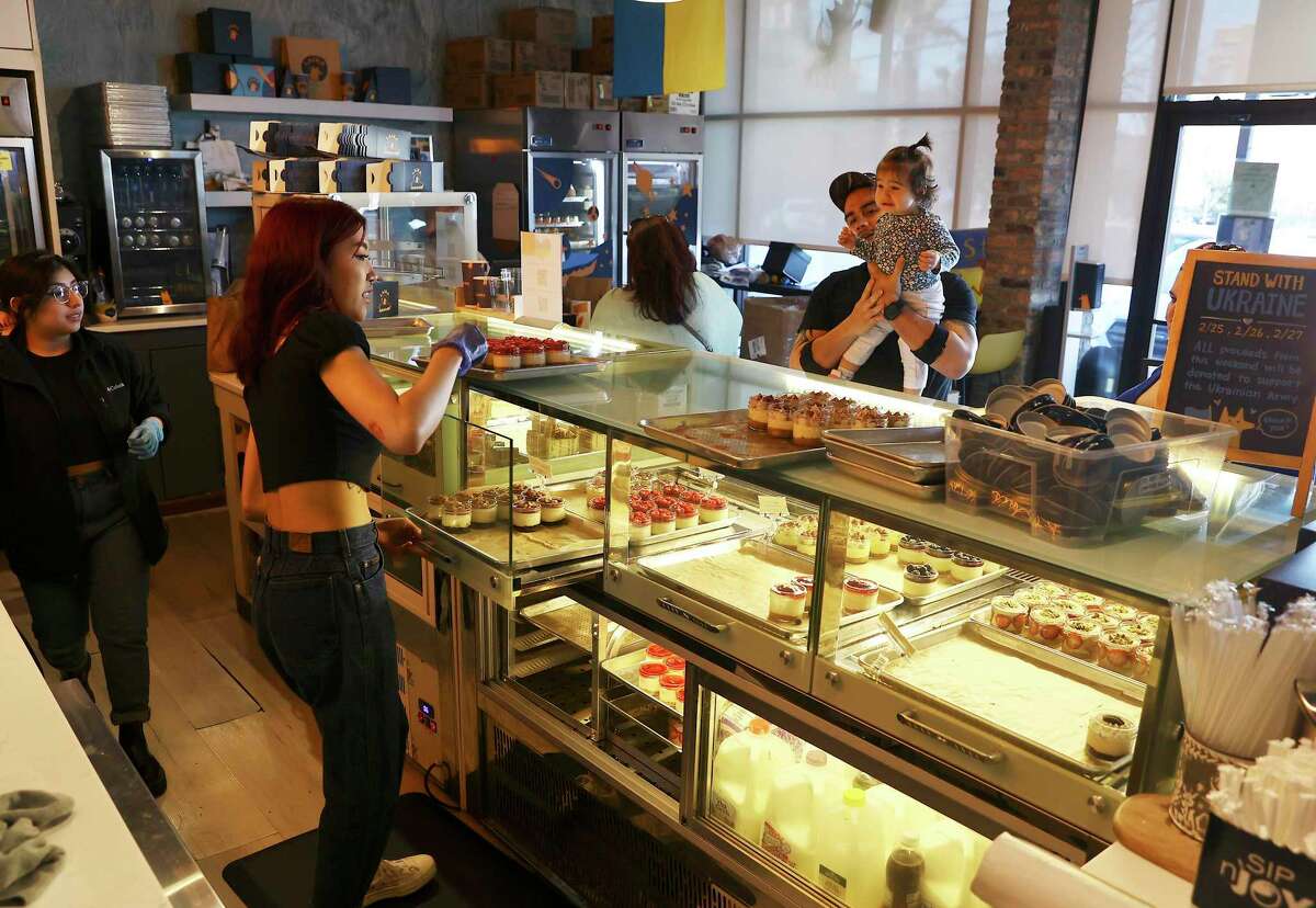 Employee Melissa Jiang (left) helps Walter and Dennise Rosas with their daughter, Camila, choose cheesecake desserts at Laika Cheesecake & Espresso on Monday.